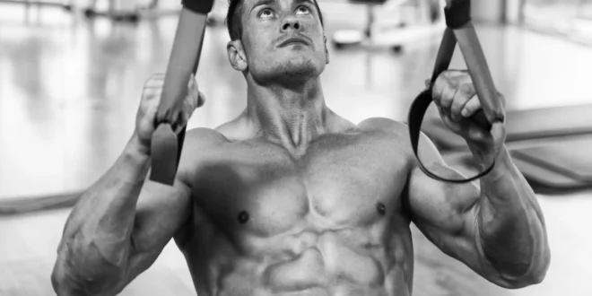 Bodybuilder trainiert hintere Schulter mit Sling Trainer